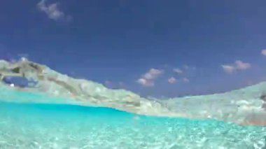 Bir el, cam şişeden Bora Bora 'nın berrak sularına su döker ve tropik cennetin özünü yakalar..