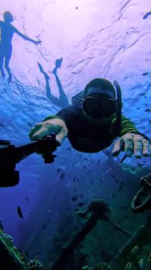 Freediver, Maldivler 'deki Keyodhoo Adası yakınlarındaki Vaavu Batığını mercanlar ve görülebilir başka bir dalgıcın uzak siluetiyle araştırıyor..