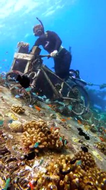 Freediver, Maldivler 'de renkli balık ve mercanlarla çevrili bir sualtı bisikletiyle etkileşim halindedir..