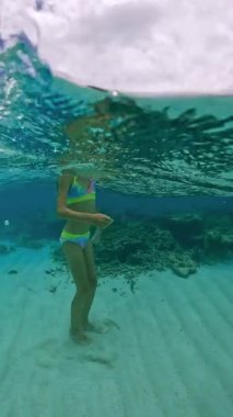 Bora Bora 'da su altında şnorkelle yüzen küçük bir kız, berrak mavi suyla mercan resiflerini keşfediyor..