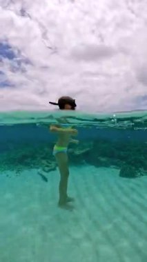 Bora Bora 'da su altında yüzen küçük bir kız, şnorkel maskesi takarak mercan resiflerini keşfediyor..