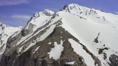 Himalayalar 'da mavi bir gökyüzünün altında engebeli, karla kaplı dağ tepelerinin havadan görünüşü.