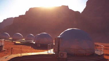 Kubbe habitatları güneş doğarken ya da batarken Mars 'ın kızıl çöl yüzeyinde bir insan kolonisini temsil eden güneş tarafından aydınlatılır..