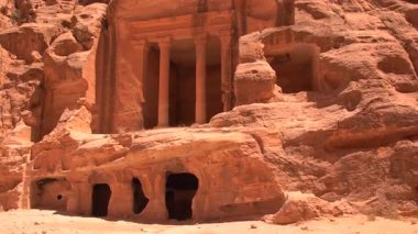 Ürdün, Petra 'daki çöl manzarasının kumtaşı kayalıklarına kazınmış sütunları olan antik kaya kesimli cephe.