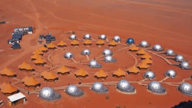Mars 'ı andıran kırmızı çöl manzarasında kubbe ve çadır yapılarından oluşan gelecekteki bir araştırma ya da turist kolonisinin hava görüntüsü.