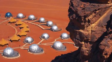 Mars 'ı andıran kızıl çöl manzarasında baloncuk çadırları ve yapıları olan bir araştırma ya da turizm kolonisi manzarası.