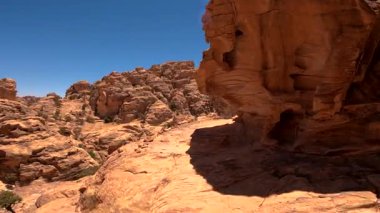 Ürdün 'de açık mavi gökyüzünün altında kırmızı kumtaşı oluşumları ve çöl kanyonu manzarası.