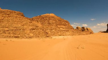 Ürdün, Wadi Rum 'da berrak mavi bir gökyüzü altında yükselen kumtaşı kaya oluşumları ile engin çöl manzarası boyunca perspektif görüntüsü..
