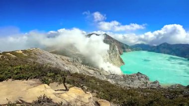 Ijen volkanik kalderasının kayalık sırtına bakın. Buharın yükseldiğini ve turkuaz asitli krater gölü, Doğu Java, Endonezya.