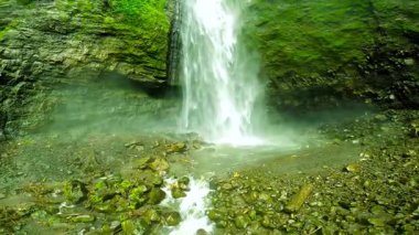 Şelale yosunlu kayalardan kayalık bir havuza dökülüyor. Bereketli yeşil kayalık yüzeyi düşen suyu sarar. Doğu Java, Endonezya 'da yer almaktadır.