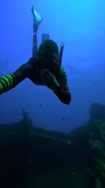 Endonezya, Bali 'deki USAT Liberty Wreck' te bir erkek serbest dalgıç su altında yüzüyor. Gemi enkazı yakınlarında diğer dalgıçlar ve balıklar görülebilir. Su sporları, seyahat ve dalış için uygundur.