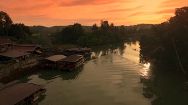 Gün batımında kürek çeken bir adamla küçük bir teknenin havası. Kenetlenmiş tur tekneleri ve yeşil ağaçlar Amazon Nehri 'nin kıyısında..