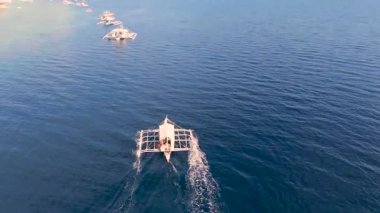 Filipinler 'in Moalboal, Cebu, Filipinler kıyıları yakınlarındaki berrak mavi okyanus suyunda yüzen birkaç geleneksel Filipinli tahrip teknesinin havası..