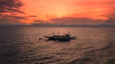 Turuncu ve kırmızı bir günbatımı gökyüzünün altında, dağlarla, Ilig Iligan, Boracay, Filipinler.