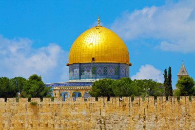 Fotoğraf kayanın ikonik altın kubbesini gösteriyor. İsrail 'in Eski Kudüs şehrindeki kutsal bir yer. Kubbe pırıl pırıl altından yapılmıştır ve mavi gökyüzüne karşı duran karmaşık desenler ve tasarımlar içerir.. 