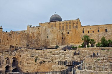 Fotoğraf, Kudüs 'teki güzel El-Mescid el-Aksa camisini, ikonik altın kubbesi, karmaşık kemerleri ve kolonları ve etrafındaki avlusuyla yakalıyor..