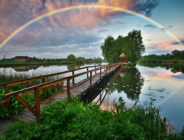 stock image picturesque rainbow over a wooden hut on a small island. fairytale house