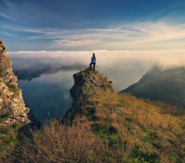 Kadın nehir kanyonunun üstündeki bir kayanın üzerinde duruyor. Dişi turistler sisli sonbahar manzarasının tadını çıkarırlar. Ukrayna 'nın doğası