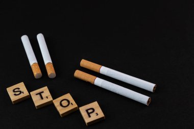 Sigara ve tahta bloklar siyah arka planda dur kelimesini gösteriyor..