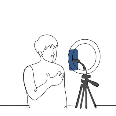 man broadcasts while standing in front of a phone camera mounted on a ring lamp - one line art vector. concept live stream of a male blogger clipart