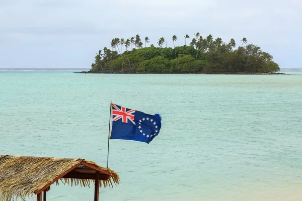 The flag of the Cook Islands, on the back of a boat in Muri Lagoon, Rarotonga, Cook Islands. In the background is tiny Taakoka Island