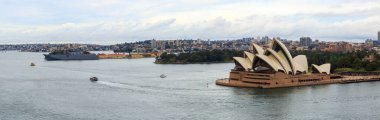 Panoramic view of Sydney Harbour, taking in the Opera House and the HMAS Canberra docked at Garden Island Naval Base. June 5, 2024 clipart