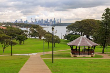 Watsons Bay, Sydney, Avustralya 'daki Robertson Park' ın arka planında liman manzarası ve şehrin ufuk çizgisi var.