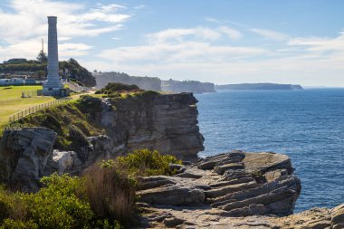Kuzey Bondi, Sydney, Avustralya 'daki sahil kayalıkları. Solda alışılmadık bir turistik yer var: Kuzey Bondi Kanalizasyon Havalandırması, 1910 'da inşa edilmiş kalıtsal bir havalandırma bacası.