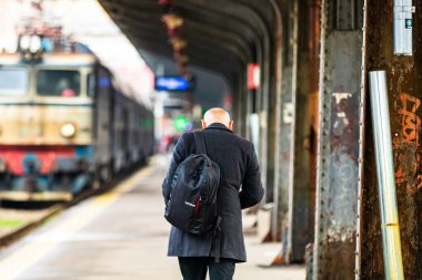 Tourist pulling luggage. Commuters walking at railroad station platform in Bucharest, Romania, 2022