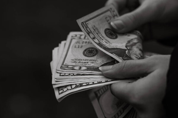 Выборочный акцент на деталях банкнот USD. Подсчет и выдача банкнот в долларах США. Концепция мировых денег, инфляция и экономика