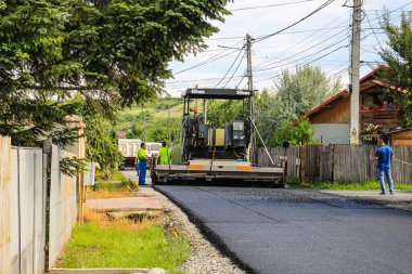 İşçiler ve asfaltlama makineleri. Romanya 'nın Bükreş kentinde inşaat ve yeni karayolunun asfaltlanması, 2022