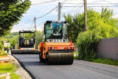 İşçiler ve asfaltlama makineleri. Romanya 'nın Bükreş kentinde inşaat ve yeni karayolunun asfaltlanması, 2022