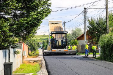 İşçiler ve asfaltlama makineleri. Romanya 'nın Bükreş kentinde inşaat ve yeni karayolunun asfaltlanması, 2022