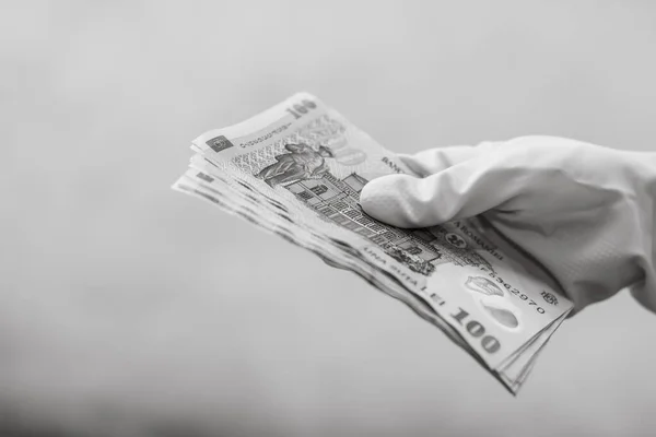 Hand with gloves receiving, giving or holding Romanian LEI  banknote. World money concept