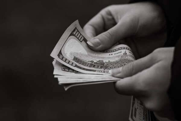 Selective focus on detail of USD banknotes. Counting or giving United States Dollars banknotes. World money concept, inflation and economy concept