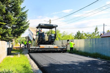 İşçiler ve asfaltlama makineleri. Romanya 'nın Bükreş kentinde inşaat ve yeni karayolunun asfaltlanması, 2022