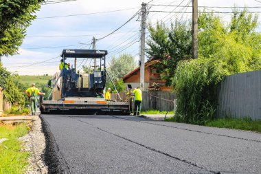 İşçiler ve asfaltlama makineleri. Romanya 'nın Bükreş kentinde inşaat ve yeni karayolunun asfaltlanması, 2022