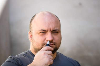 Erkek tıraş makinesi ya da jilet kullanarak burun kıllarını kesiyor.