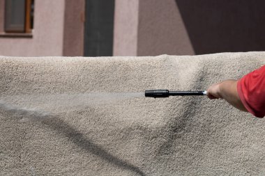 Yüksek basınçlı yıkamalı halılar. Yüksek basınçlı suyu yıkamak için halıyı silahla temizlemek.