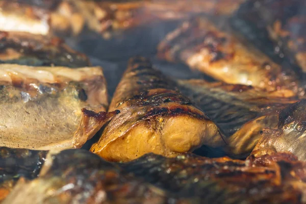 stock image Grilled mackerel fish with smoke on a charcoal barbecue grill.