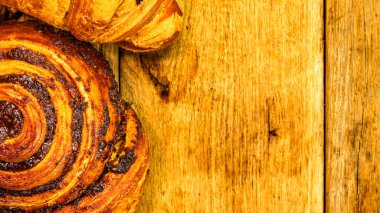 Renkli çörekler, poğaça ve bisküviler ahşap masada. Jöleli şekerli tatlı yiyecekler, çikolatalı donutlar. Kopyalama alanı olan üst görünüm
