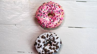 Beyaz ahşap masada renkli çörekler. Şekerli, şekerli, şekerli, şekerli, şekerli. Kopyalama alanı olan üst görünüm