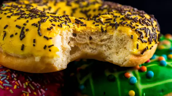 Кусатый Желтый Пончик Глазурью Изолированными Посыпками Крупный План Красочных Пончиков — стоковое фото
