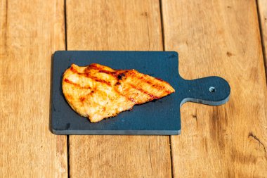 Izgara bifteği, izole edilmiş küçük siyah kesme tahtasına yakın tut. Barbekü, ızgara ve yemek konsepti.