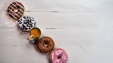 Beyaz ahşap masada renkli çörekler. Şekerli, şekerli, şekerli, şekerli, şekerli. Kopyalama alanı olan üst görünüm