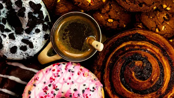 Ahşap masada renkli çörekler. Jöleli şekerli tatlı yiyecekler, çikolatalı donutlar. Kopyalama alanı olan üst görünüm