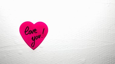 Handwriting text love you on heart shaped memo post reminder. Romantic love concept for Valentine`s day.
