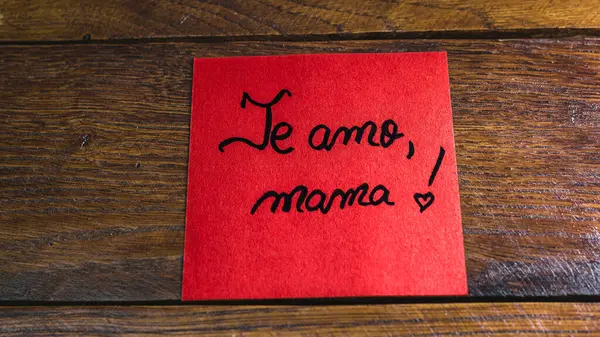 Writing I love you, mom in Spanish (te amo, mama) on memo post reminder. Text on sticky paper. Mother`s day concept.