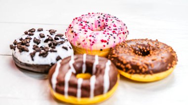 Beyaz ahşap masada renkli çörekler. Şekerli, şekerli, şekerli, şekerli, şekerli. Kopyalama alanı olan üst görünüm