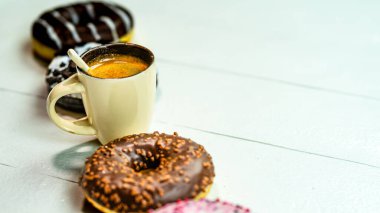 Beyaz ahşap masada renkli çörekler ve kahve fincanı. Jöleli tatlı fırın, kahvaltı konsepti. Kopyalama alanı olan üst görünüm